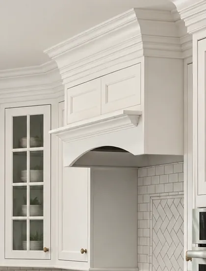 Fitted range hood and glass-front cabinet meeting the crown molding
