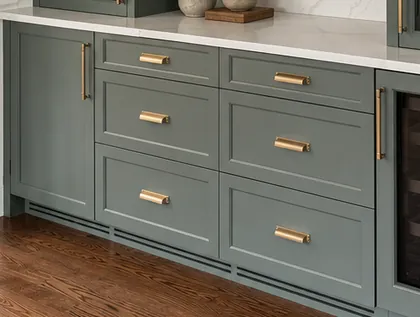 Brass pulls on green painted drawer fronts under a stone counter